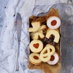 Biscotti di pasta frolla senza glutine con farine naturali ripieni di marmellata di albicocche e ricoperti di zucchero a velo e cioccolato fondente