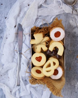 Biscotti di pasta frolla senza glutine con farine naturali ripieni di marmellata di albicocche e ricoperti di zucchero a velo e cioccolato fondente