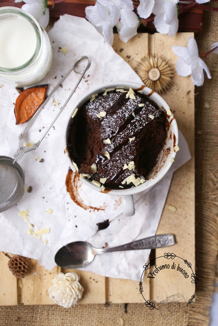 Mug Cake o torta in tazza senza glutine al cioccolato, con cioccolato fuso, zucchero a velo e scaglie di cioccolato bianco in superficie 