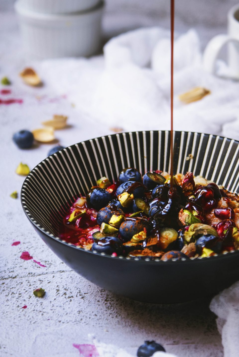 Porridge senza glutine con fiocchi di avena, mirtilli, melograno, pistacchi e sciroppo d'acero.